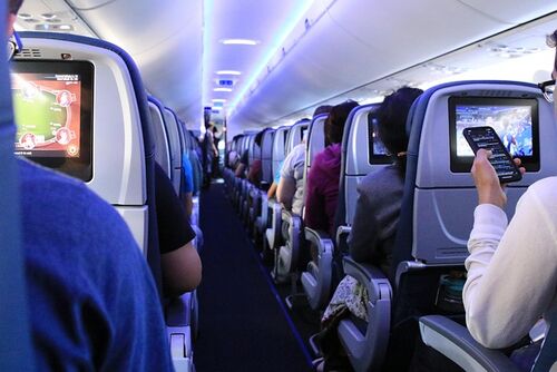 Blick in eine voll besetzte Flugzeugkabine mit Passagieren in ihren Sitzen | Sabine Verheyen
